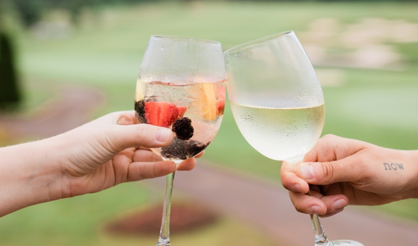 Mill River Resort couples retreat Duo toast with wine glasses with golf course in background