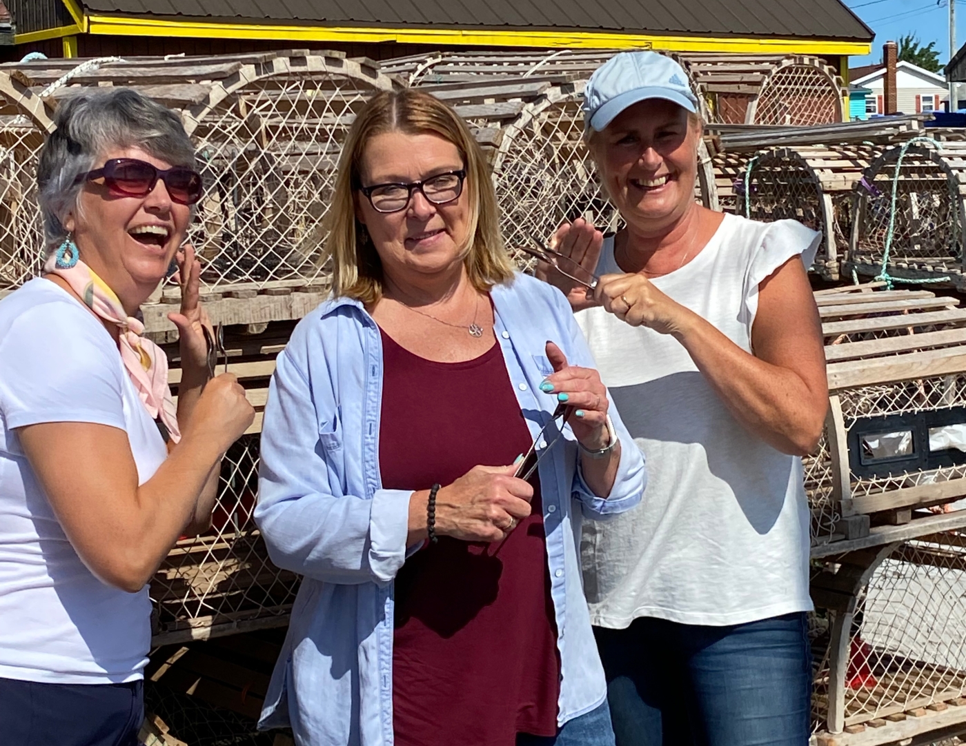 PEI Spoon Guy Three women stand in front of lobster traps playing the spoons