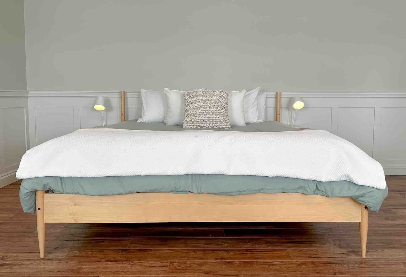 Modern, sleek bed with white duvet and soft green accents