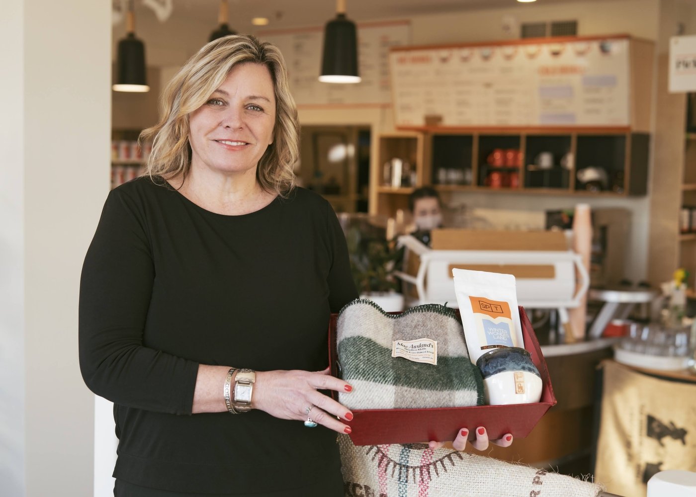 Samuel's owner, Moyna Matheson, holds gift basket inside her coffee shop