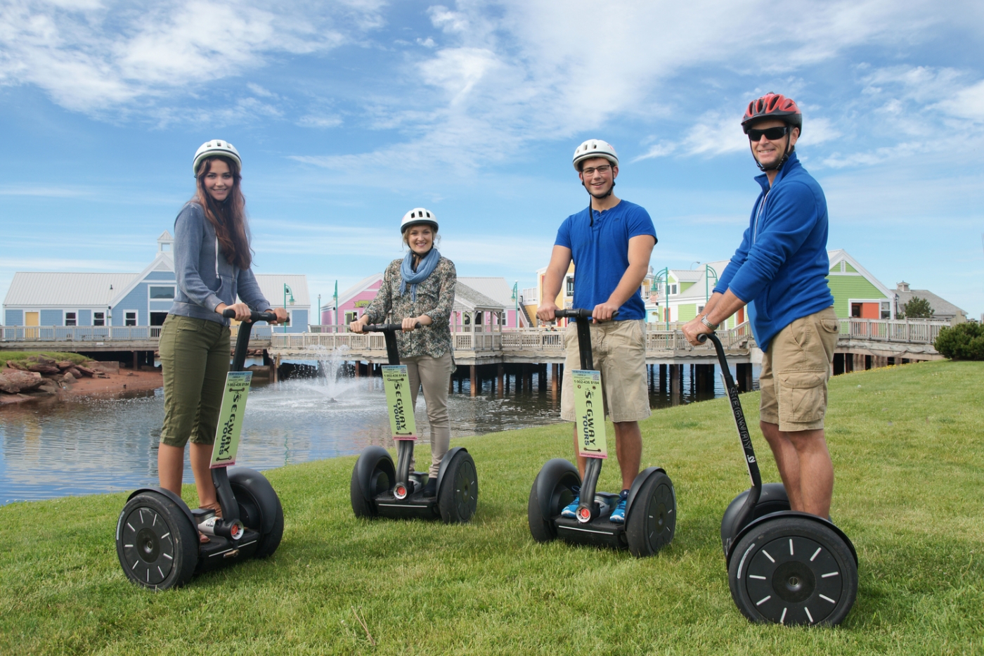 Four adults wearing helmets riding out for a ride on Segways