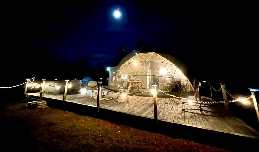 Exterior view of dome at Shoreline Retreat Ltd. at night under full moon