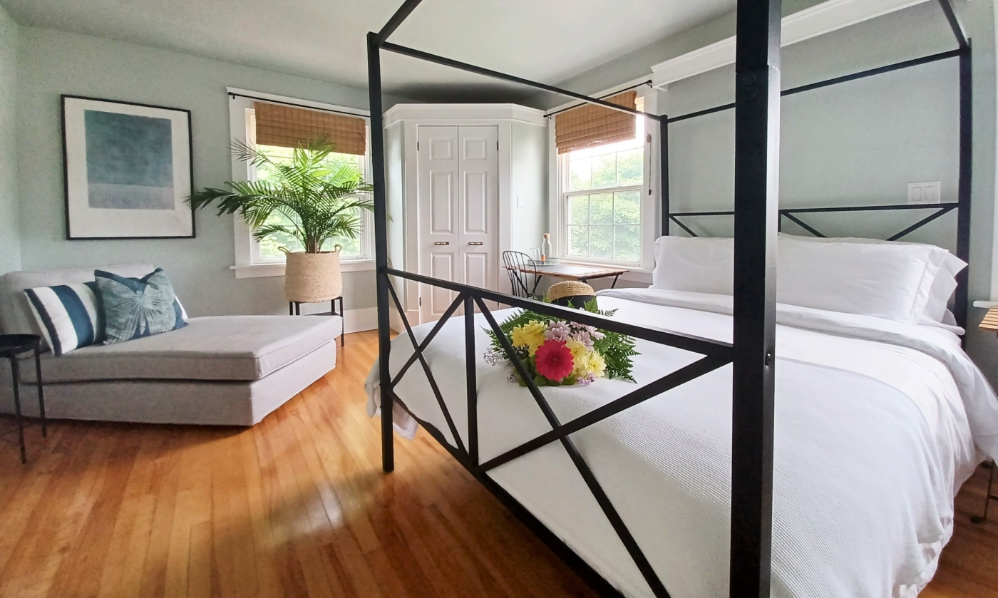 Bedroom with metal canopy bed, light walls and natural wood floors