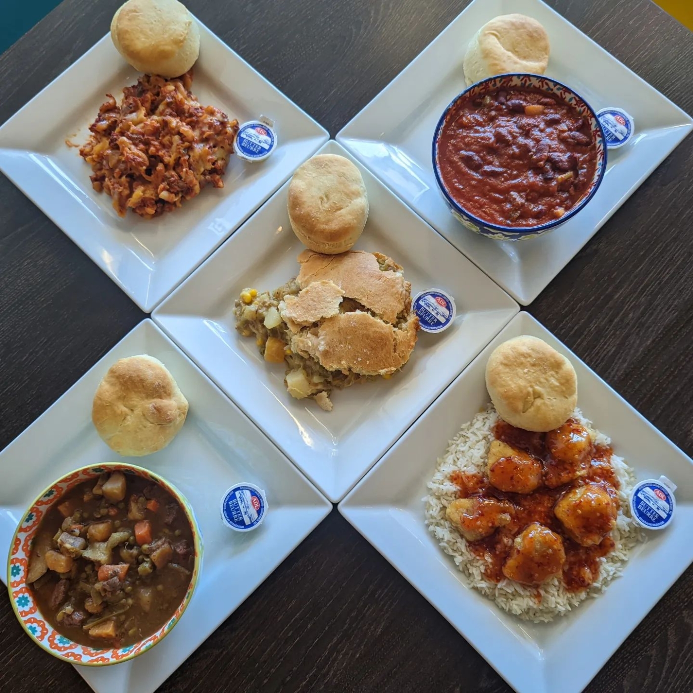 Five plates of lunch menu items displayed each with a biscuit and butter