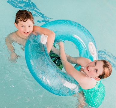 Two children hold on to floatie in swimming pool