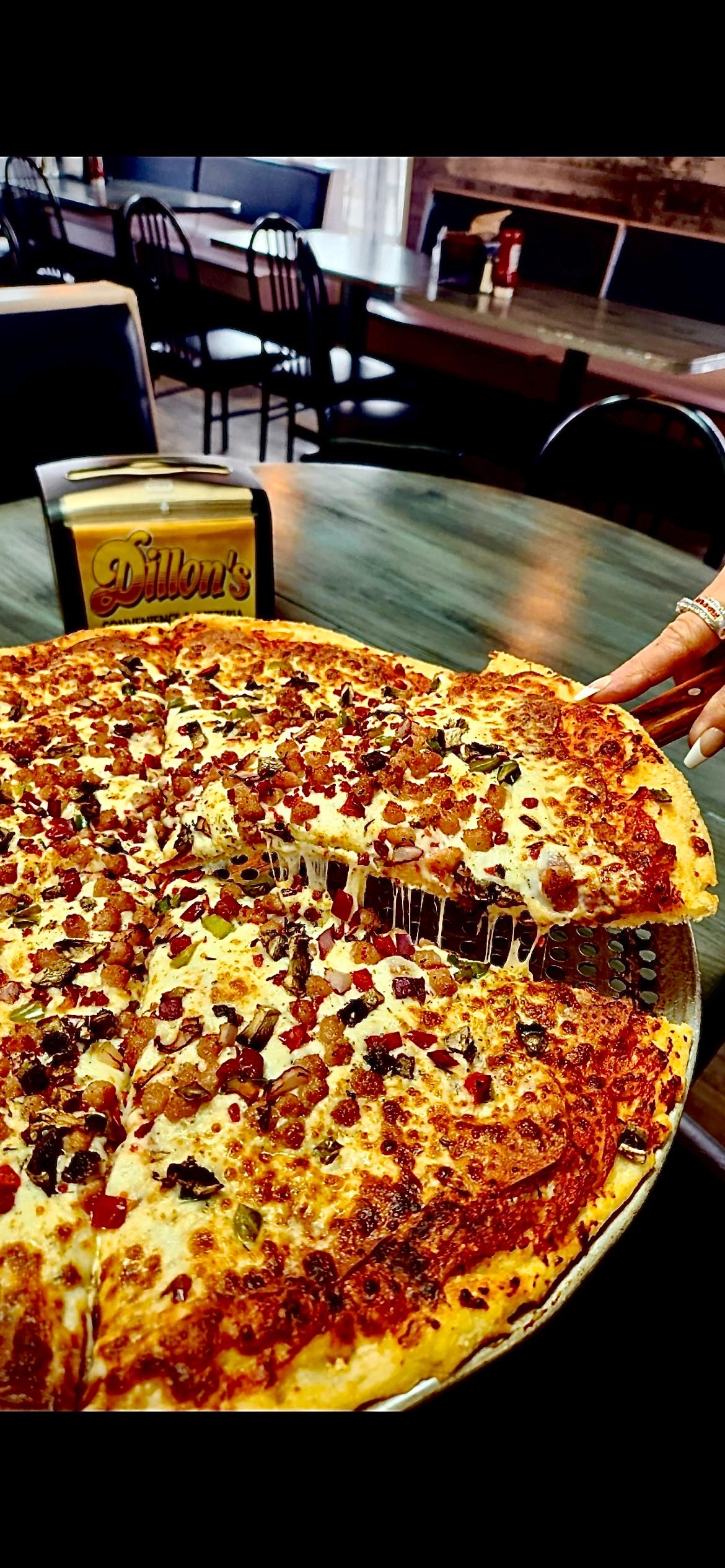 Large pizza sitting on table with Dillon's logo on napkin holder in background