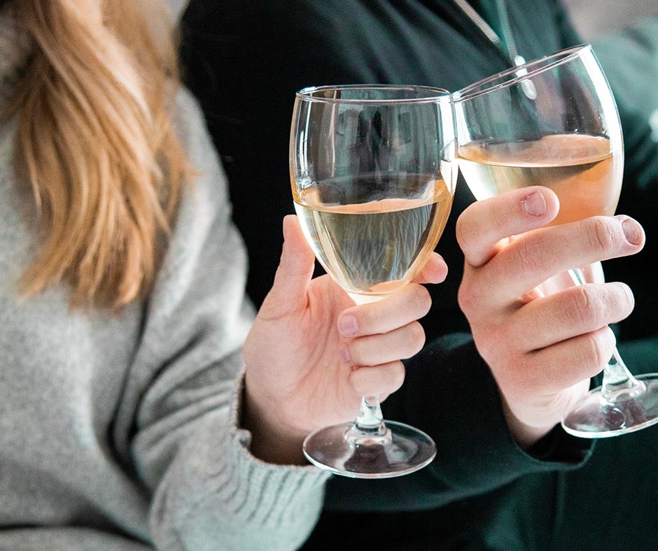 photo of two peoples hands holding wine