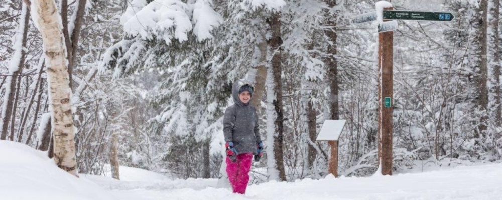 Child in snow gear walks on Farmlands Trail at PEI National Park