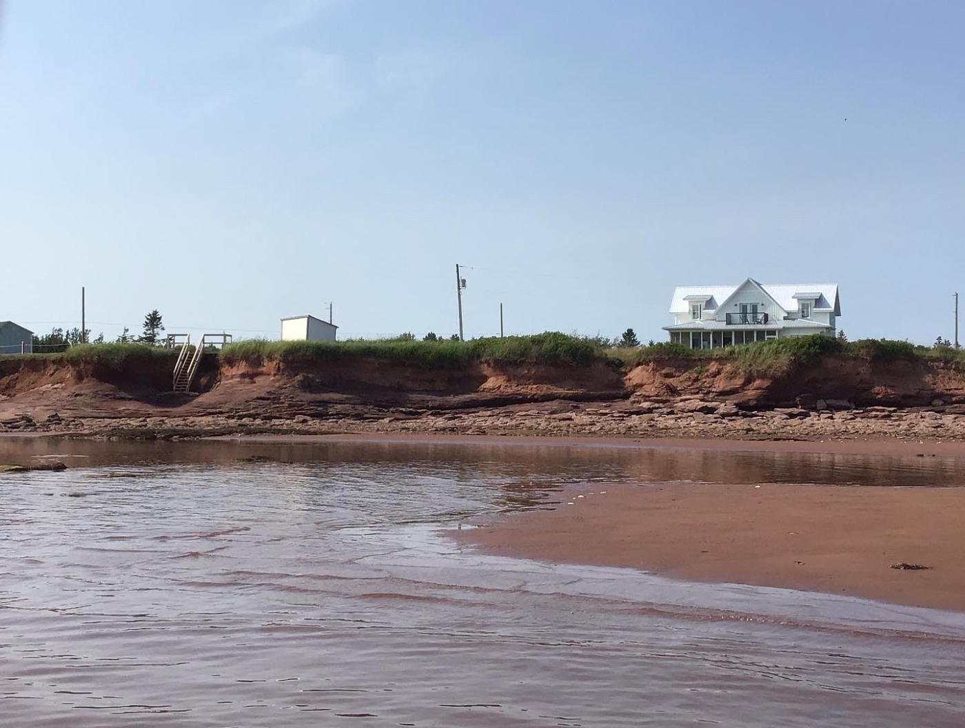 beautiful view from the water showing Gerada's oceanfront Beach House on the high red cliffs