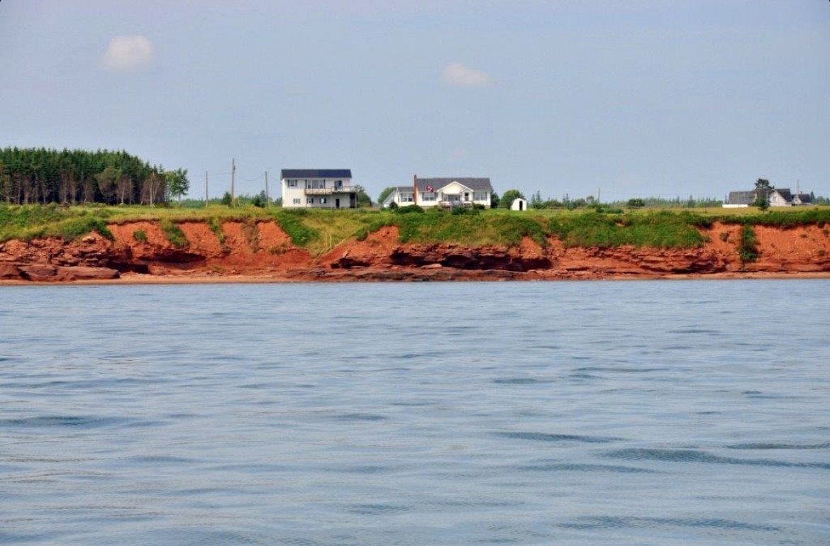 photo taken from the water looking at cliffs and Kate's cove retreat cottage on the bank