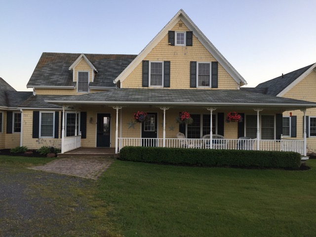 Manor on the Pond large yellow with brown shutters and large deck on front of this beautiful country home