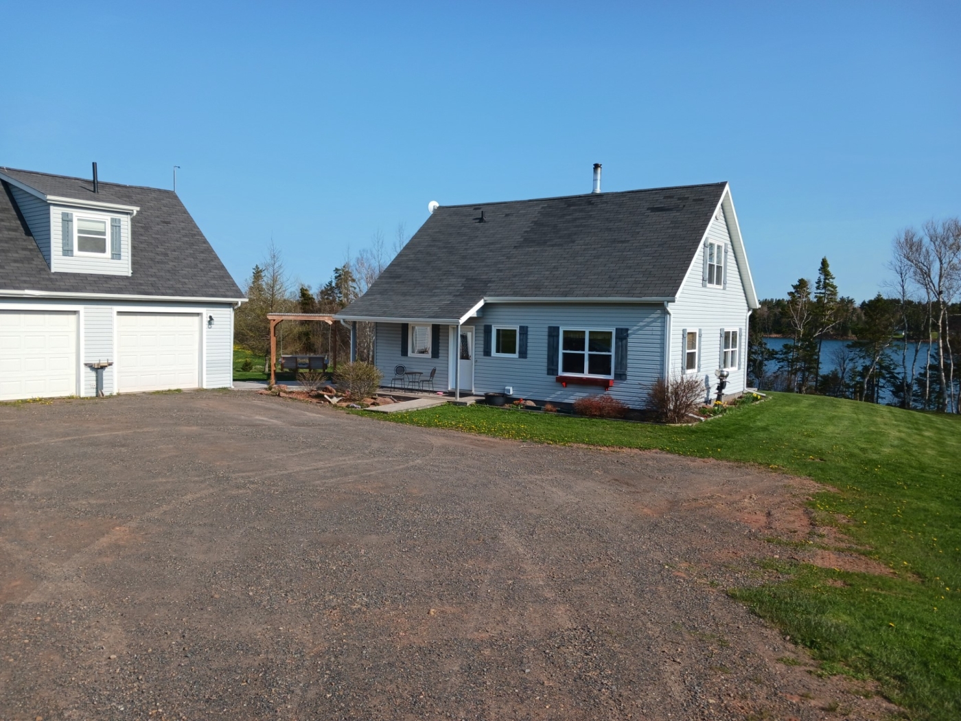 The Cozy Loft outside view looking up the driveway to a garage and grey cottage